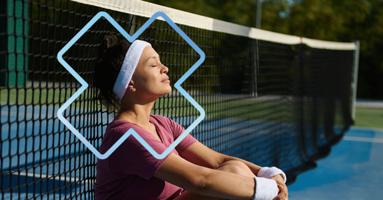 Personne assise au sol, adossée à un filet de tennis, portant un bandeau et des poignets absorbants, sur un terrain extérieur, dans un contexte de récupération et de gestion de la performance sportive.