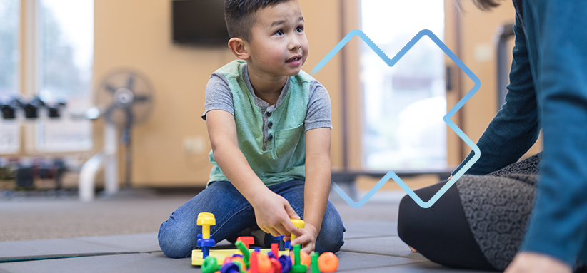 Enfant effectuant des exercices de motricité au sol dans un contexte de physiothérapie pédiatrique.