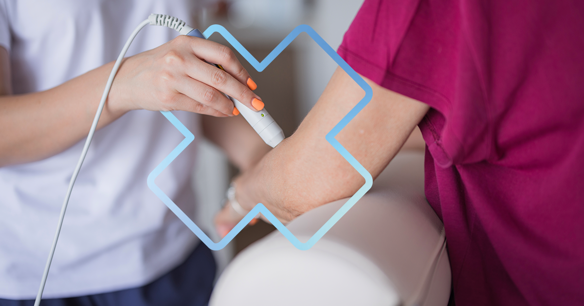 Application de thérapie par ondes de choc sur le coude d’un patient à l’aide d’un appareil portatif en clinique de physiothérapie.